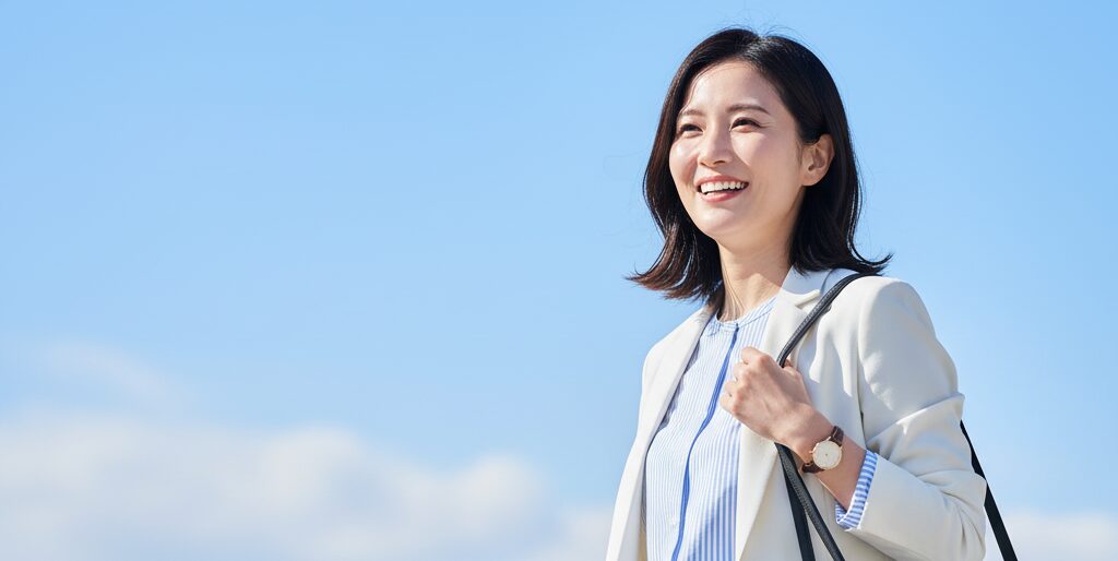 屋外で青空を背景にして気持ちの良い笑顔の女性